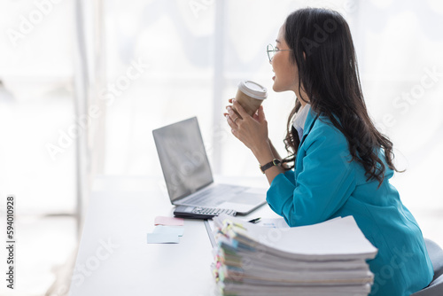 Portrait of Asian business woman holding coffee cup with work in workplace office Business documents money financial planning concept 