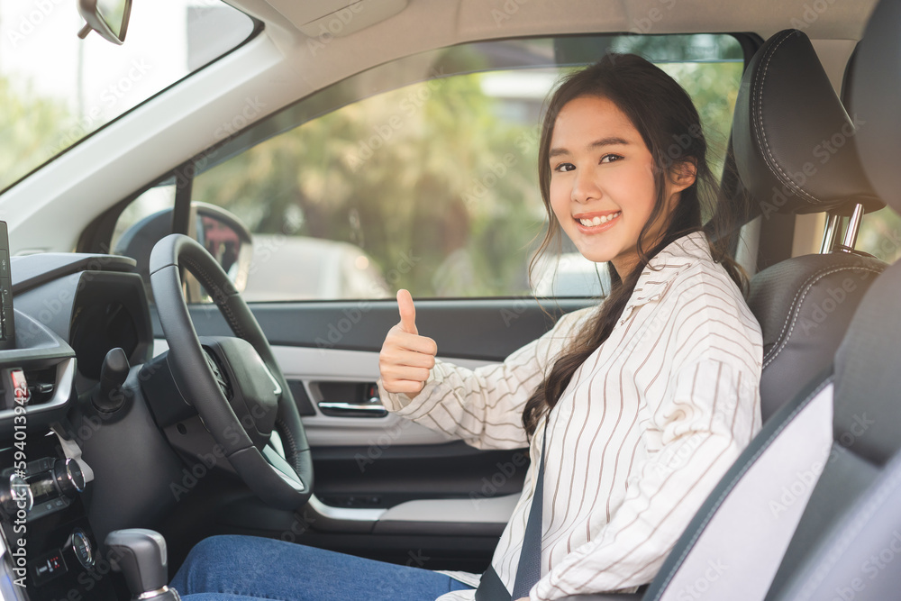 Happy smile asian young woman showing thumb up, fastens a seat belt sitting of car before driving, vehicle for travel, trip take a safe journey, attractive driver with safety belt, transportation.