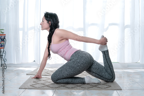 mature beautiful woman doing yoga pilates and stretching exercises in the comfort of her home happy and calm