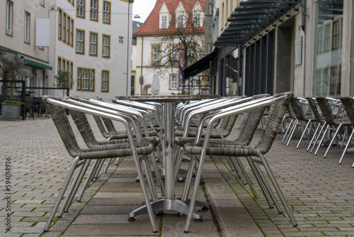 Empty tables in Bielefeld cobblestone alley.
