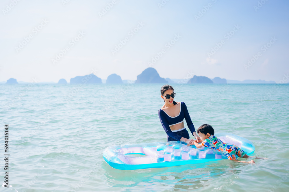 The boy and his mother are playing with a swim ring in the sea and having fun.