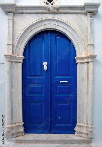 Greece.Tinos island, Blue home entrance door with marble arch frame on white wall,