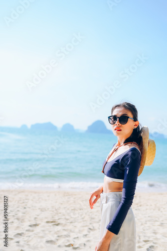 The woman wearing sunglasses is relaxing on the sandy beach.
