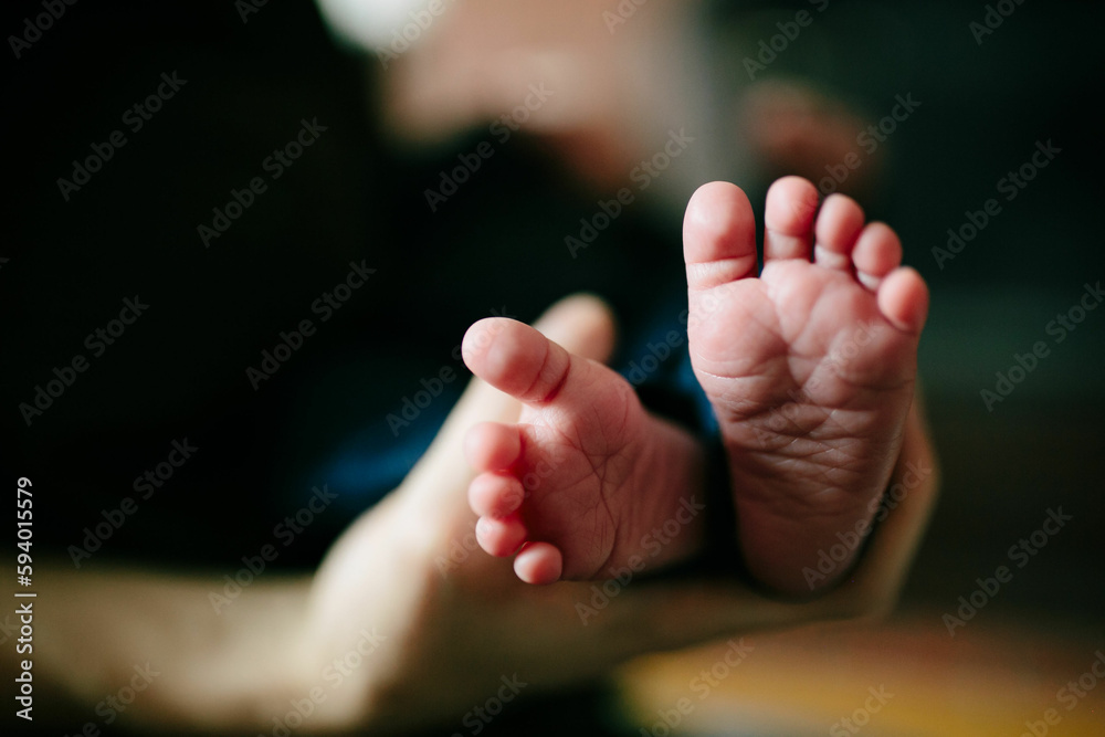 dad's hand holding caucasian newborn's feet dad's hand holding caucasian newborn's feet