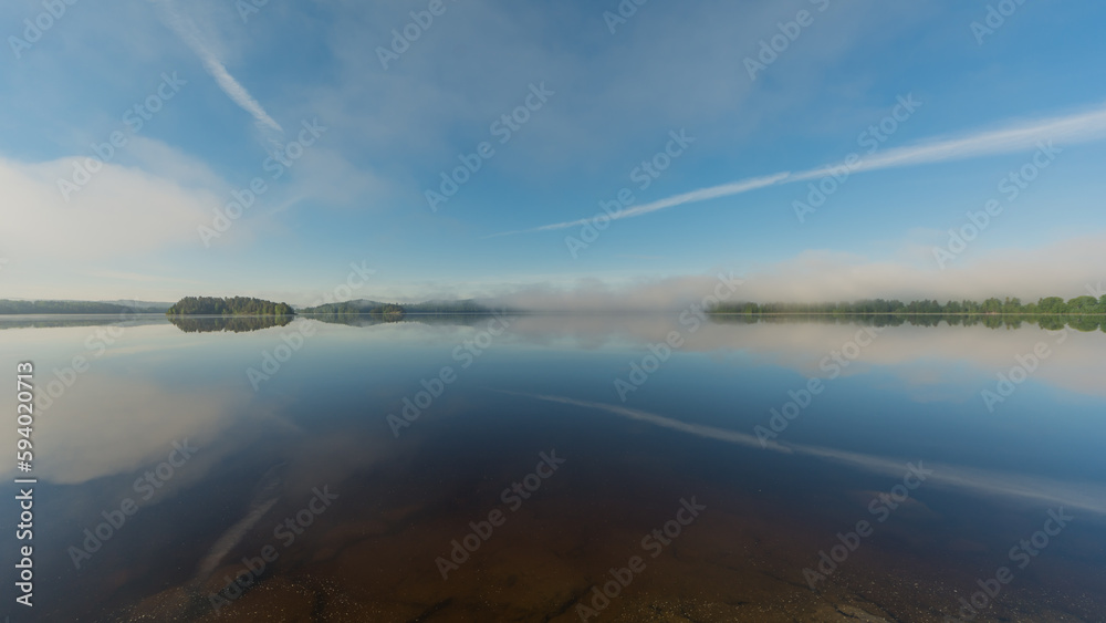 Summer lake scenery with clouds and mist reflected on the water in Finland Summer lake scenery with clouds and mist reflected on the water in Finland