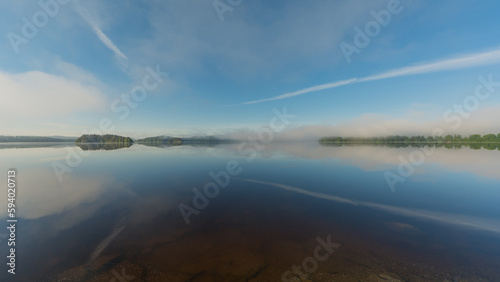 Summer lake scenery with clouds and mist reflected on the water in Finland