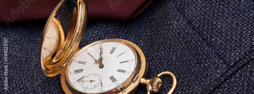 Golden pocket watch on the background of a man's suit.Retro style and vintage fashion.