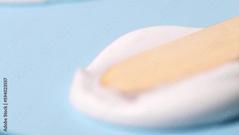 A sample of a cosmetic cream for moisturizing and skin care, a smear with a wooden spatula on a blue background.
