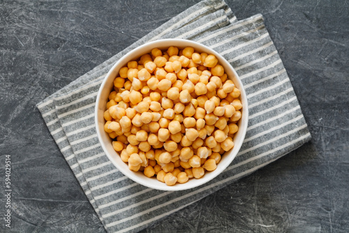 Cooked or canned chickpeas in a white bowl on a table, top view.