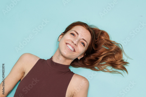 Joyful young excited woman wearing a red shirt. Happy and smiling cheerfully ginger hair woman portrait over mint studio background. Confident fit female. Happiness and lifestyle people.