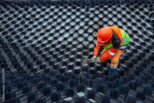 Ust-Luga, Leningrad oblast, Russia - November 16, 2021: Worker installing HDPE Geocell Ground Grid Paver. Plastic Geocell For Construction