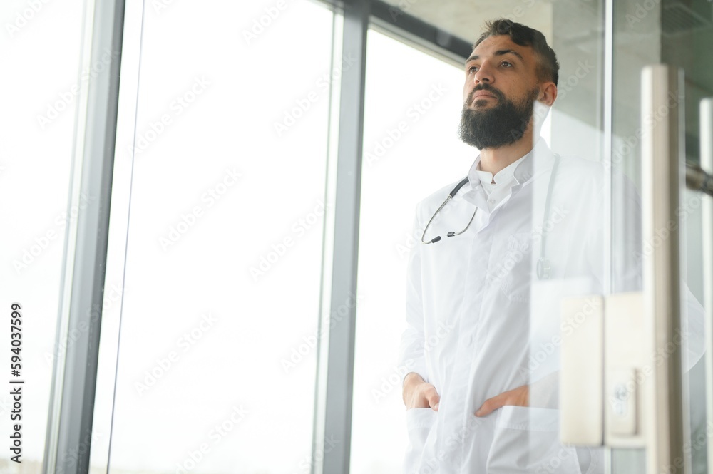 Fototapeta premium Portrait of pleasant young Arabian doctor in white coat.