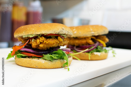 Two burgers with breaded chicken fillet in a restaurant kitchen