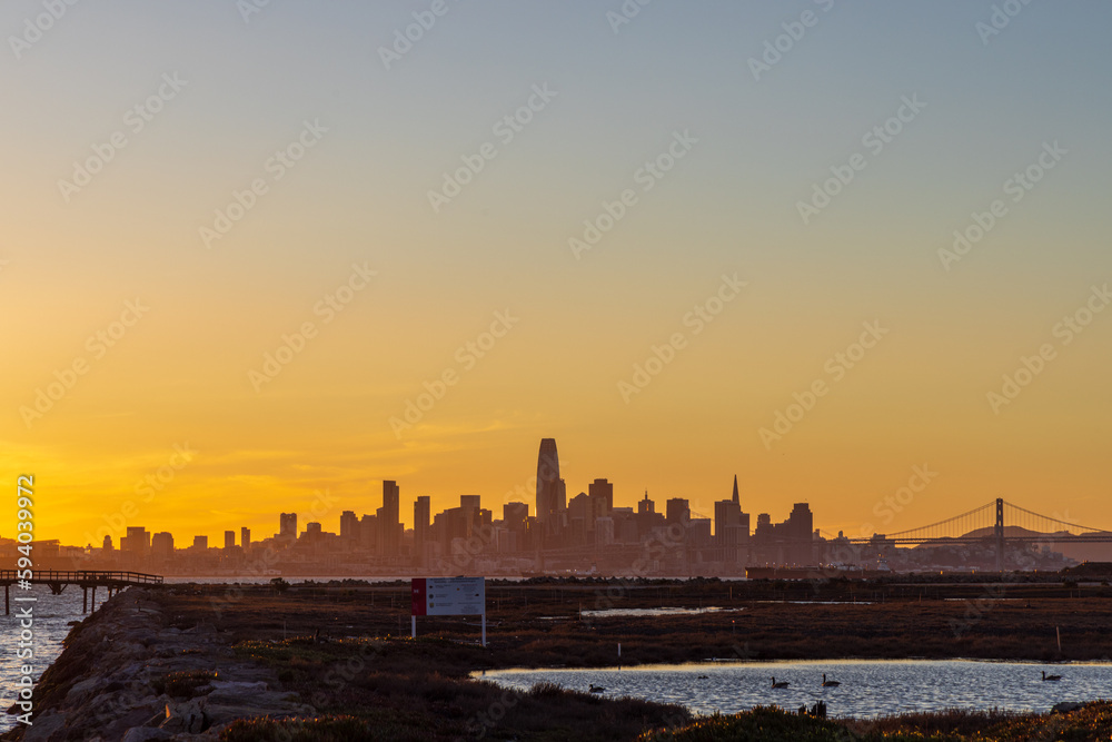 A view of the city of San Francisco from across the bay at sunset with a silhouette of the cityscape