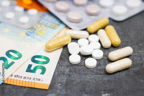 White round pills, capsules, blister packs with tablets, antibiotic, painkiller or drugs and money, Euro currency banknotes, expensive medicine and healthcare concept, close-up view