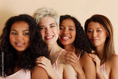 Four young females with different skin tones looking at the camera. Diverse women standing together.