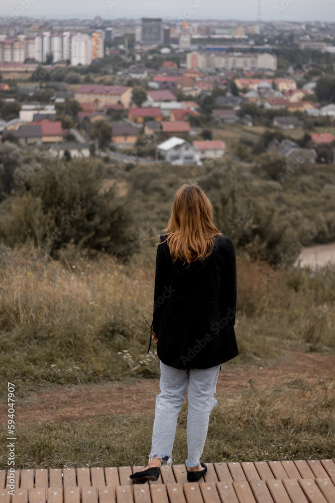 Redhead woman standing and looking at the city 