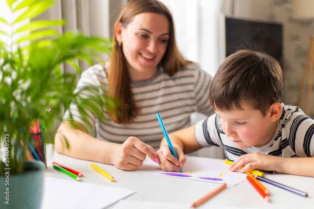 Mother and child drawing with pencils sitting at the desk at home Mother and child drawing with pencils sitting at the desk at home
