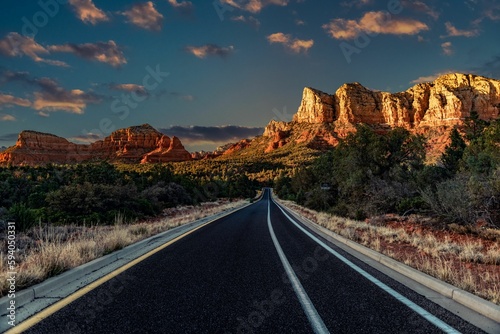 Highway going through a deserted place in Sedona with rock formation ahead, Arizona