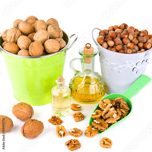 Walnut kernels, nuts in a bucket and bottled nut oil isolated on white .
