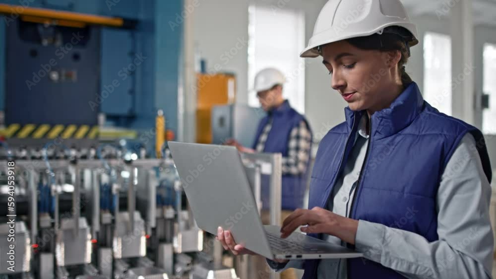 Close-up portrait of beautiful middle-aged female engineer looking watching at product making process. Woman nodding and putting information into her big grey gadget. Close-up portrait of beautiful middle-aged female engineer looking watching at product making process. Woman nodding and putting information into her big grey gadget.