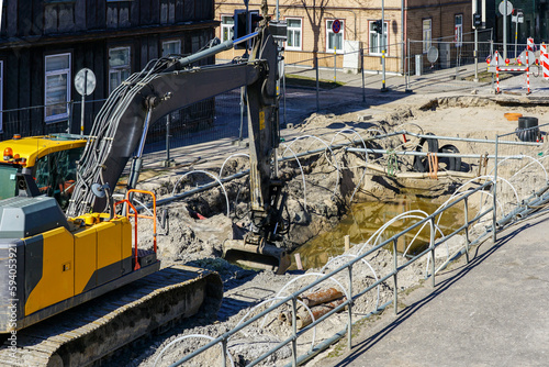 Underground communications replacement site with dewatering system and excavator on a city street