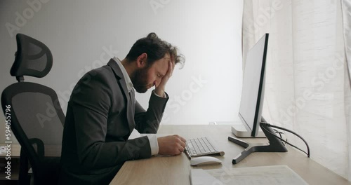 Tired lazy napping yawn adult bearded man manager worker bored at work project at Home. Young man freelancer in a gray suit using laptop studying working online at home. photo