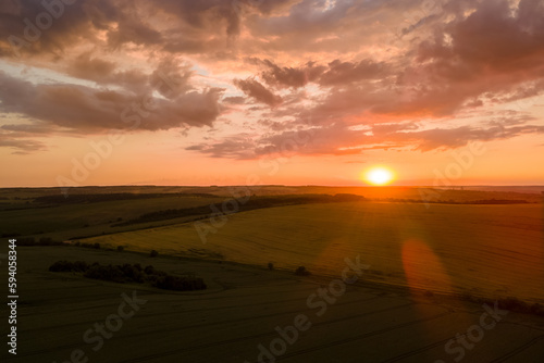 Aerial landscape view of yellow cultivated agricultural field with ripe wheat on vibrant summer evening