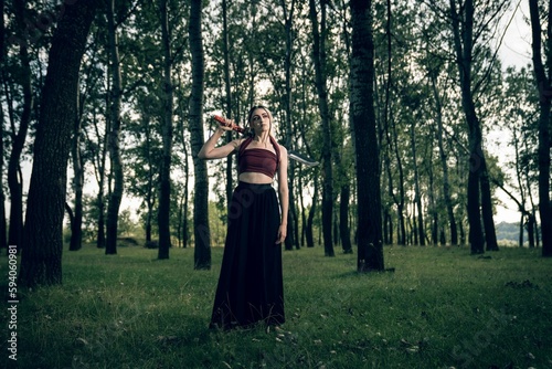 Caucasian woman holding knife and standing in forest