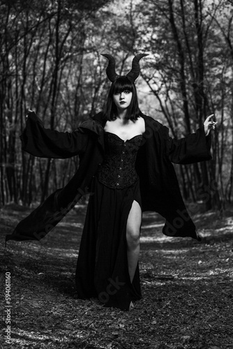 Vertical shot of a gothic girl with Maleficent horns posing in a mystic forest