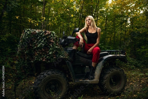 Caucasian white blonde woman on the quad bike in the green forest