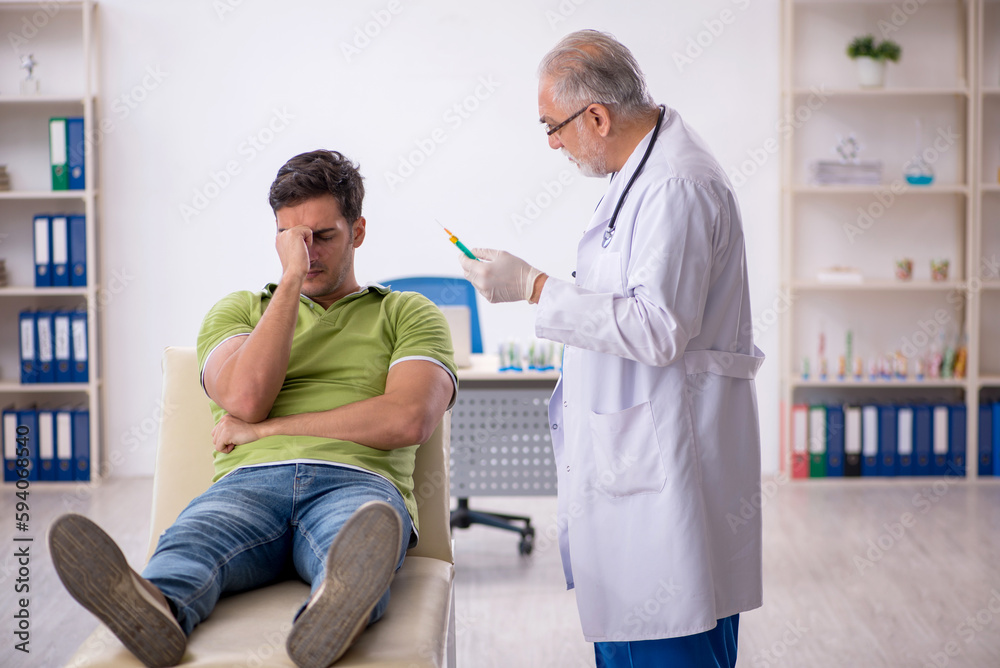 Fototapeta premium Young male patient visiting old male doctor in vaccination conce