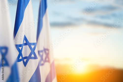 Israel flags with a star of David over cloudy sky background on sunset. Banner with place for text.