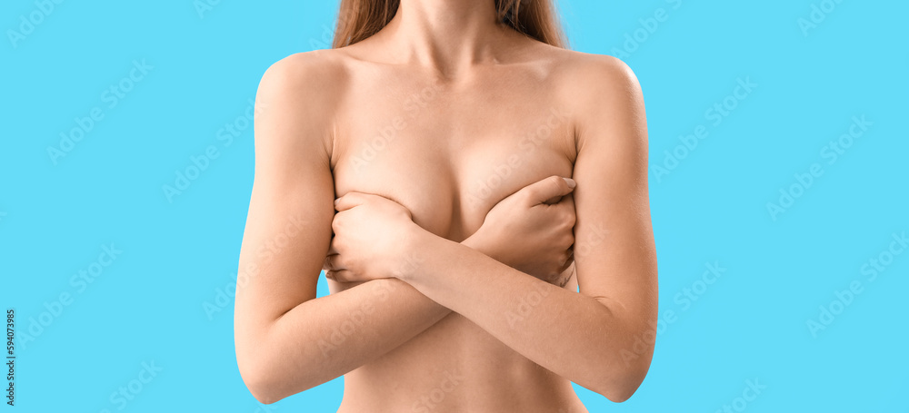 Fototapeta premium Naked young woman on light blue background. Breast cancer awareness concept
