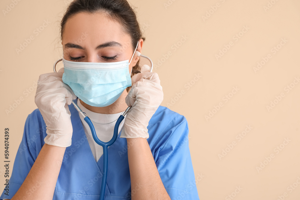 Female medical assistant with stethoscope on beige background Female medical assistant with stethoscope on beige background