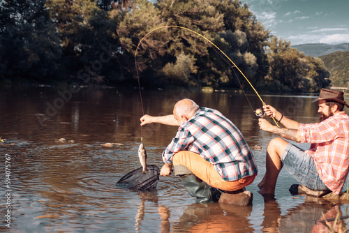 Mature senior man with friend fishing. Summer vacation. Happy cheerful people. Bearded men catching fish. Fisherman with fishing rod. Activity and hobby. Catching fish.