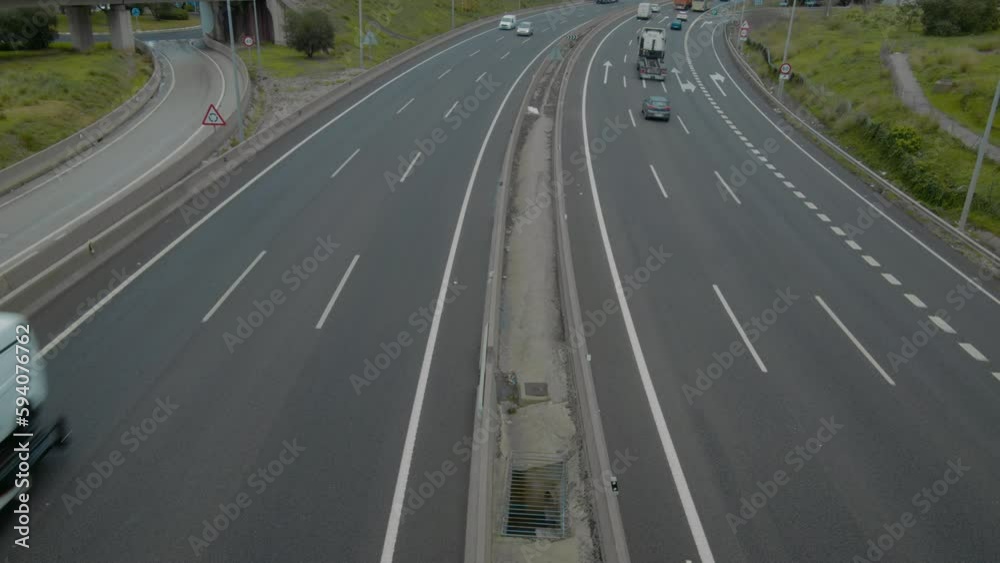 A wide shot of a highway from a high angle view. The highway has three lanes on each side and cars and trucks are speeding along A wide shot of a highway from a high angle view. The highway has three lanes on each side and cars and trucks are speeding along