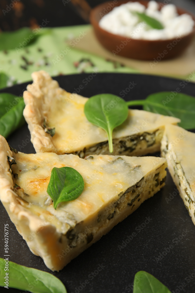 Plate with pieces of delicious quiche on black wooden background Plate with pieces of delicious quiche on black wooden background