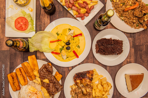 A set of Peruvian food dishes with huancaina potatoes in the center, a quesillo, steaks with rice and plantains, arros chaufa and drinks photo