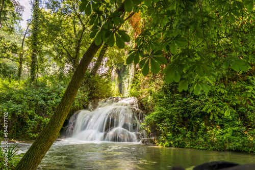 A small launa with a waterfall nestled among dense foliage photo