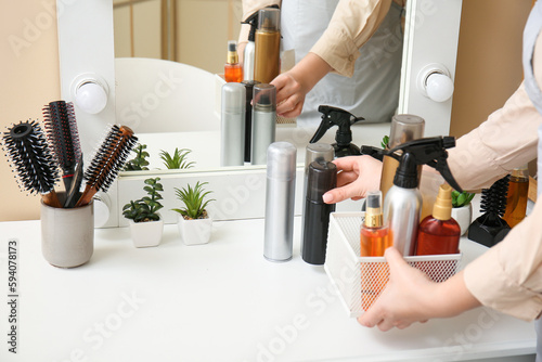 Woman putting hair spray on table in beauty salon