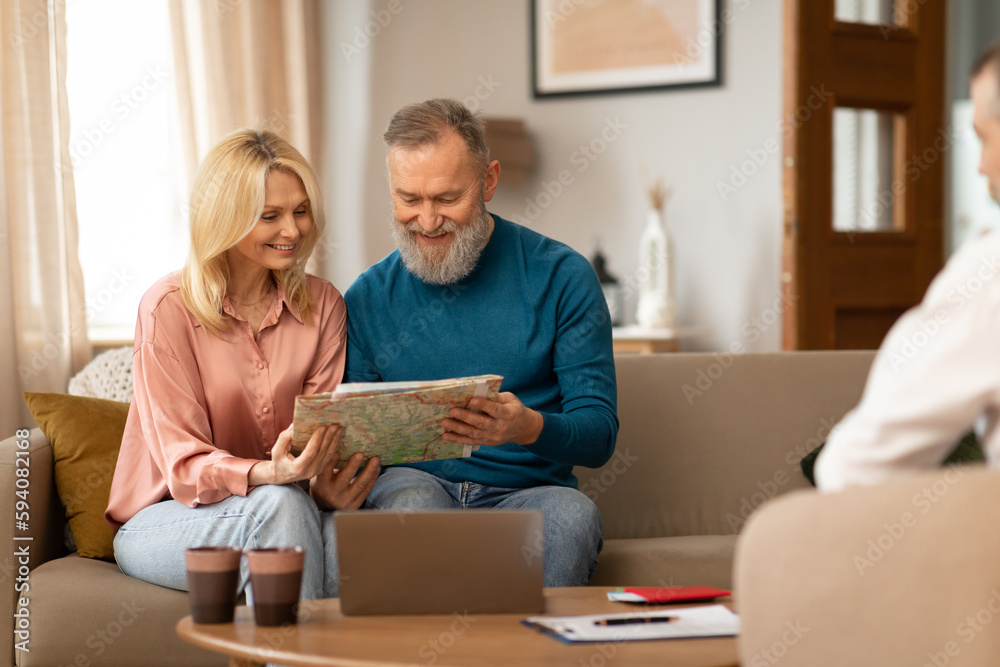 Mature Spouses Holding Map Choosing Destination With Travel Agent Indoors
