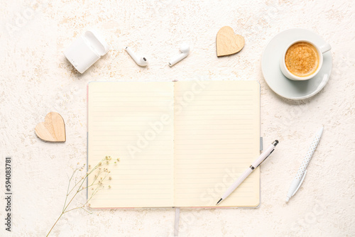 Composition with notebook, cup of coffee, gypsophila flowers and earphones on white table