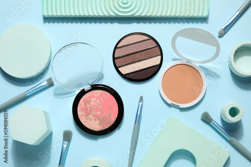 Decorative cosmetics with brushes and podiums on blue background