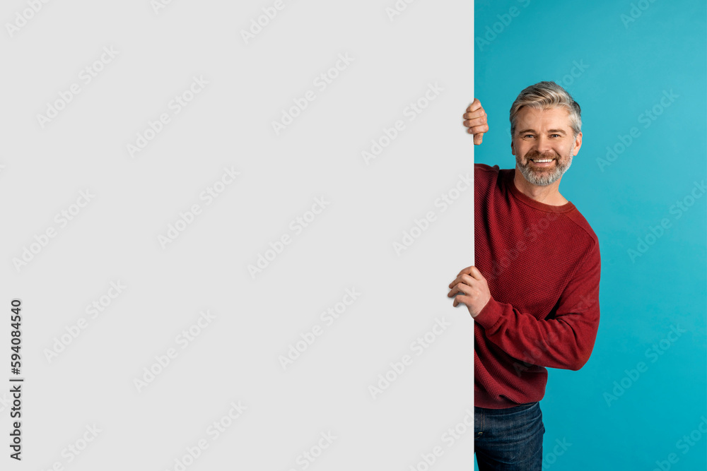 Cheerful mature man standing by huge advertisement board, mockup