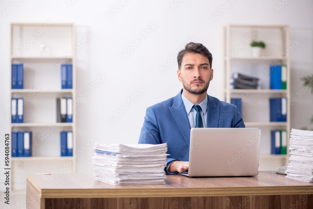 Young male employee and too much work in the office Young male employee and too much work in the office