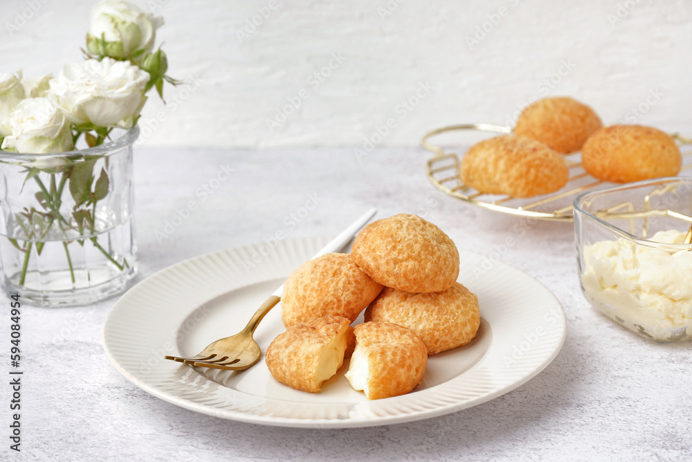 Plate with tasty choux dessert on light background