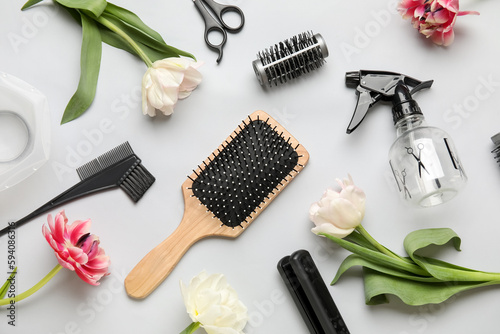 Composition with hairdresser tools and tulip flowers on grey background