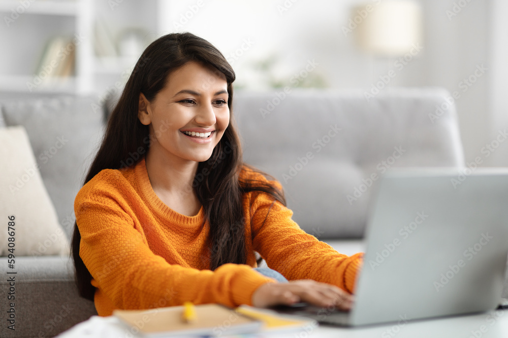 Happy indian woman digital nomad working on laptop, home interior Happy indian woman digital nomad working on laptop, home interior