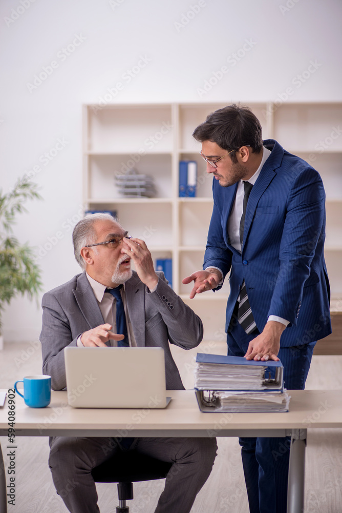 Old male boss and young male employee in the office Old male boss and young male employee in the office